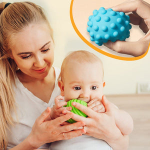 Mother helping baby explore textured sensory balls from Montessori Busy House toy set for fine motor skills development.