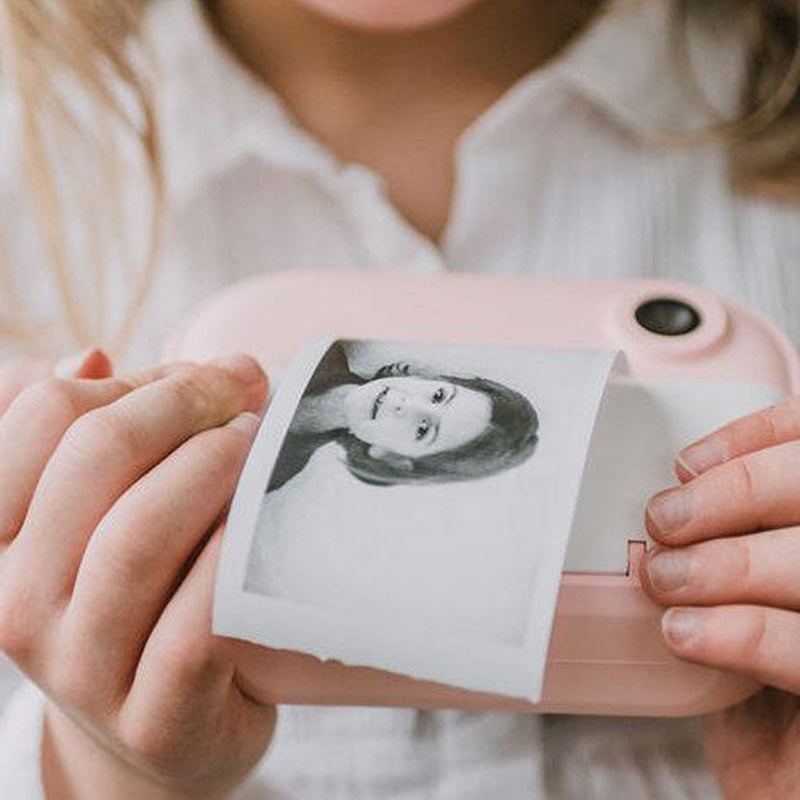 Child using pink Kid Instant Print Camera printing a black and white photo instantly