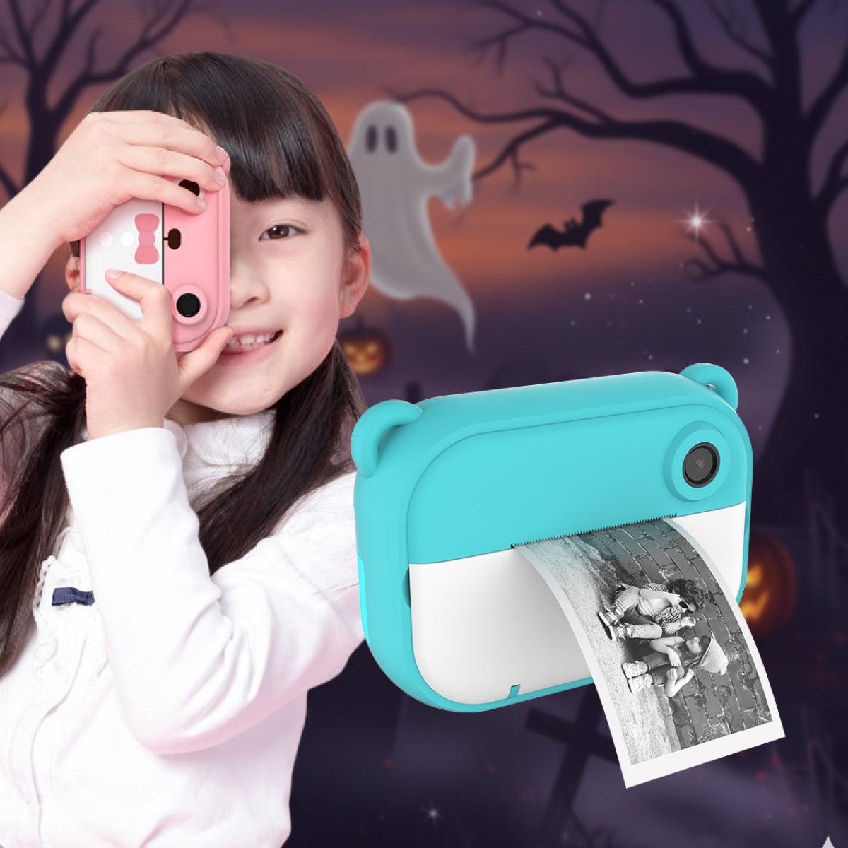 Child using pink Kid Instant Print Camera with blue camera printing photo, Halloween ghost and bats background